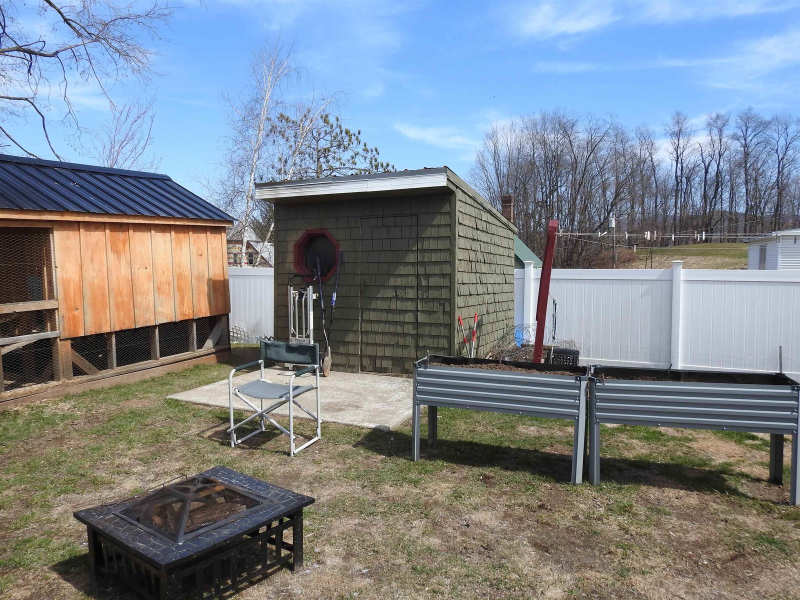 Back lawn with chicken coop, storage sheds, and raised beds.